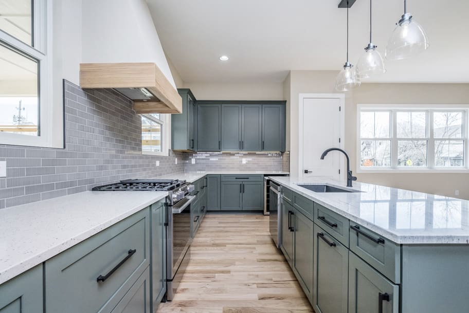 A Large Island with White Countertops and Hanging Glass Pendant Lights