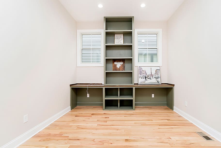 Home Office with Light Wood Floors, Green Built-In Desk, and Tall Shelving in a Custom New Construction Home by Gem Homes Indianapolis