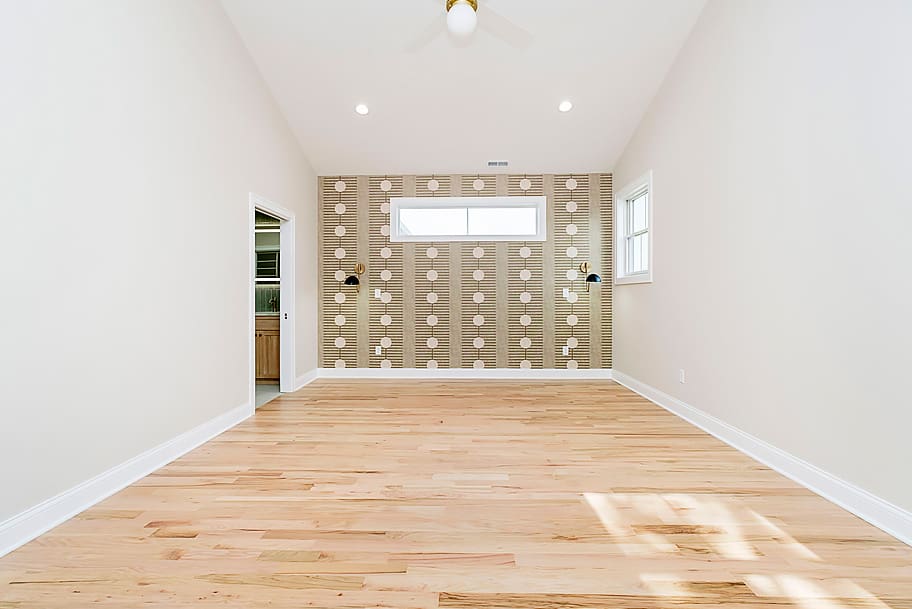 Primary Bedroom with Green Accent Wallpaper, Light Wood Flooring, and Tall Ceilings in a Custom Home by Gem Homes Indianapolis
