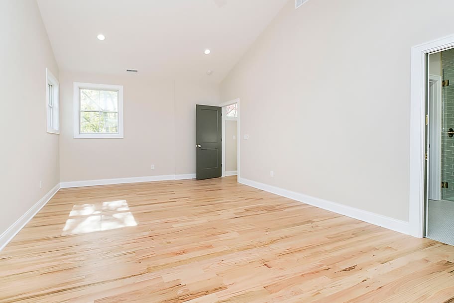 Primary Bedroom with Light Wood Flooring, Tall Ceilings, and Green Door in a Custom Home by Gem Homes Indianapolis