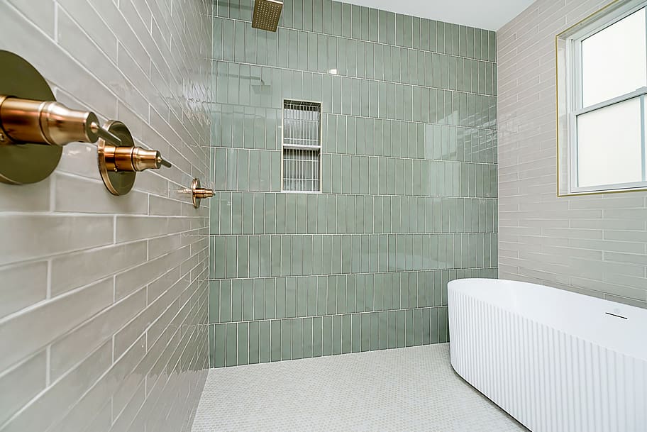 Modern Wet Room with Light Green Vertical Tile, Double Shower, and White Bathtub in a Custom Home by Gem Homes Indianapolis