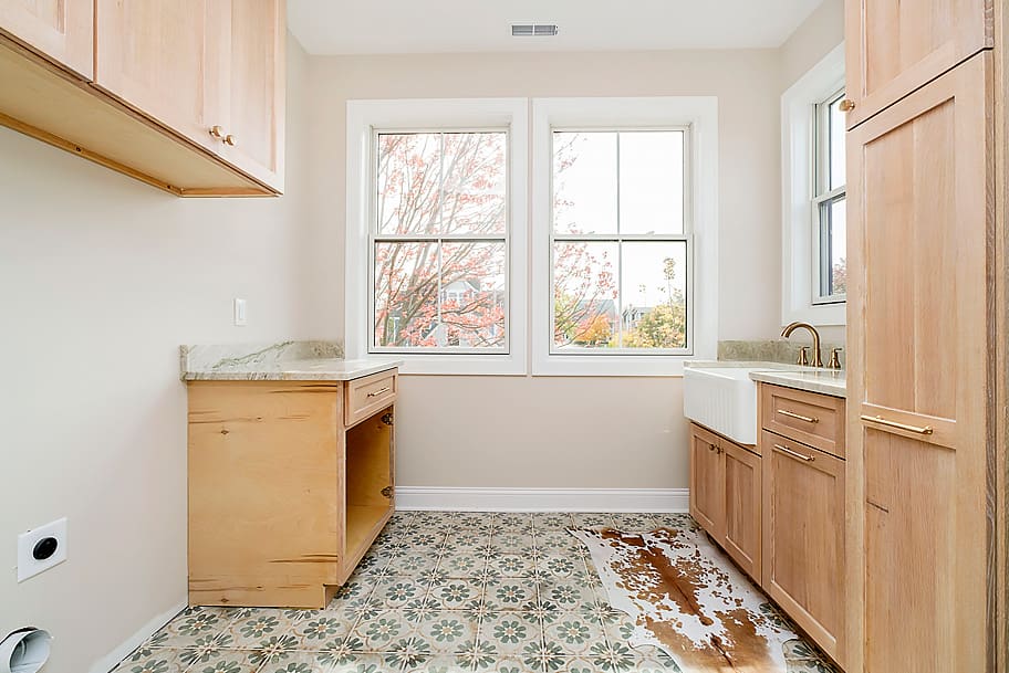 Laundry Room with Floral Tile Flooring, Light Brown Wood Cabinets, and Sink in a Custom Home by Gem Homes Indianapolis