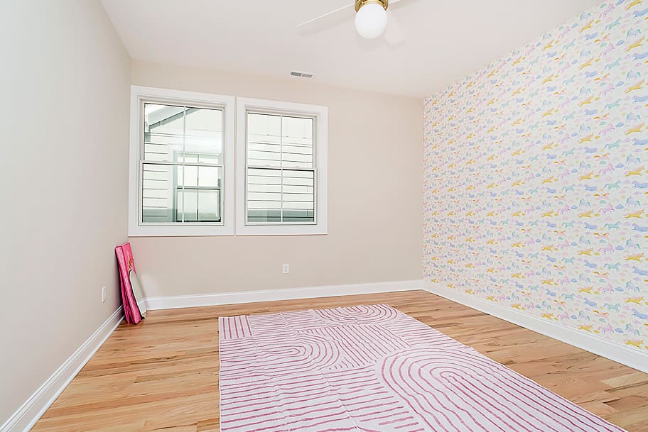 Little Girl's Room with Colorful Horse Wallpaper Accent Wall and Light Wood Flooring in a Custom Home by Gem Homes Indianapolis