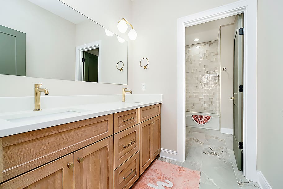 Guest Bathroom with Shower-Tub Combo, Beige Tile, Double Sinks, and Oak Wood Cabinets in a Custom Home by Gem Homes Indianapolis