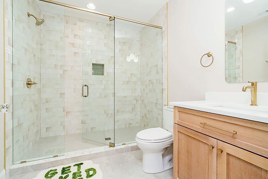 Guest Bathroom with One Sink, Large Glass Paneled Shower, Beige Tile, and Gold Accents in a Custom Home by Gem Homes Indianapolis