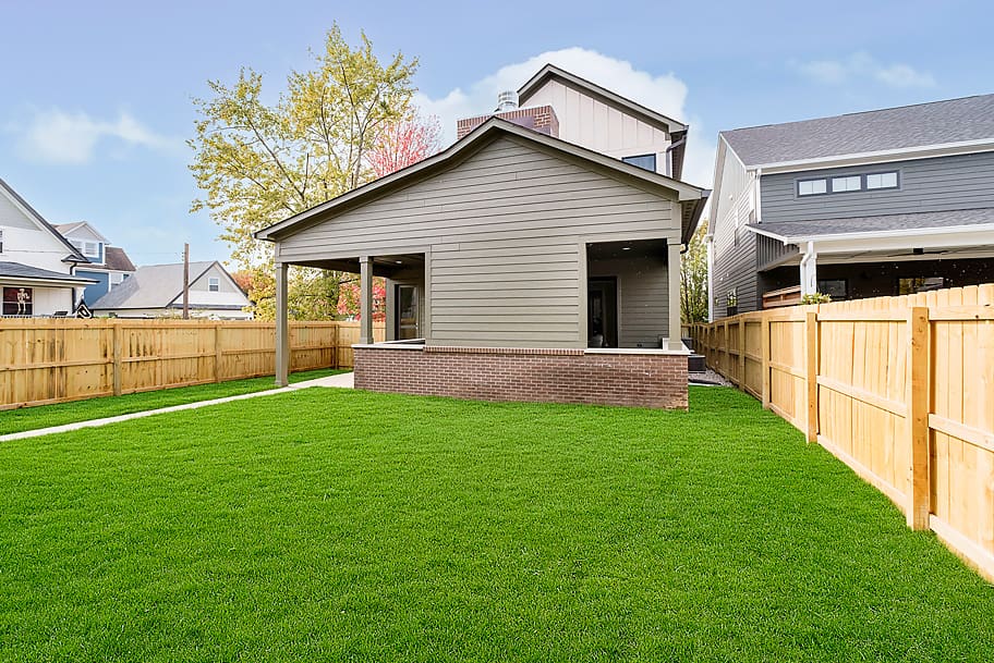 Fenced-In Yard with Green Artificial Grass and Walkway Leading to Covered Porch in a Custom Home by Gem Homes Indianapolis