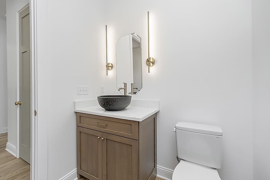 Modern Powder Room with Black Bowl Sink and Gold Accent Lighting in a Custom Home by Gem Homes Indianapolis