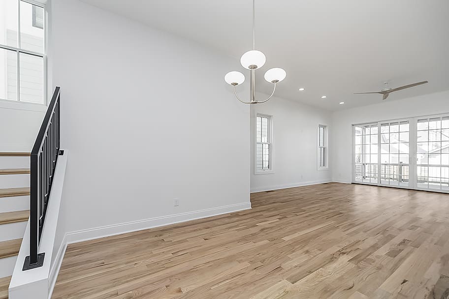 Dining Room with Hanging Light, Light Wood Floors, and Bifold Doors in a Custom Home by Gem Homes Indianapolis