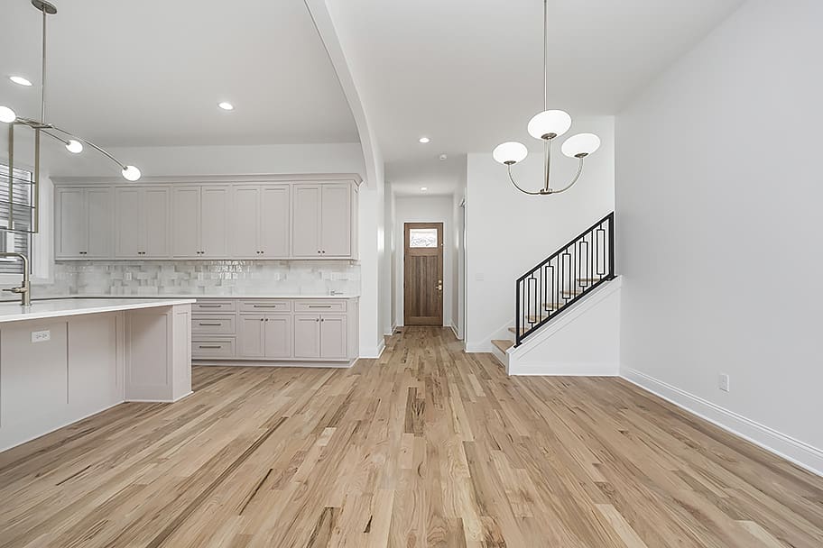 Dining Room with Hanging Light, Light Wood Floors, Stairs, and Front Door in a Custom Home by Gem Homes Indianapolis