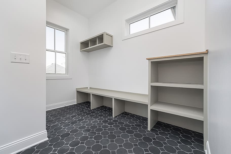 Designated Mudroom with Green Built-In Storage and Gray Circle Floor Tile in a Custom Home by Gem Homes Indianapolis