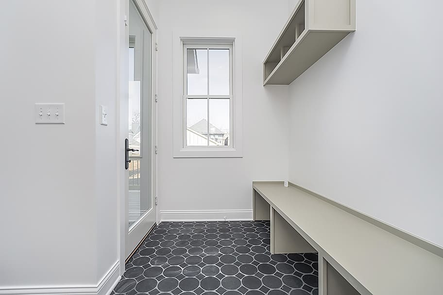Mudroom with Green Built-In Storage, Gray Circle Floor Tile, and Glass Door in a Custom Home by Gem Homes Indianapolis