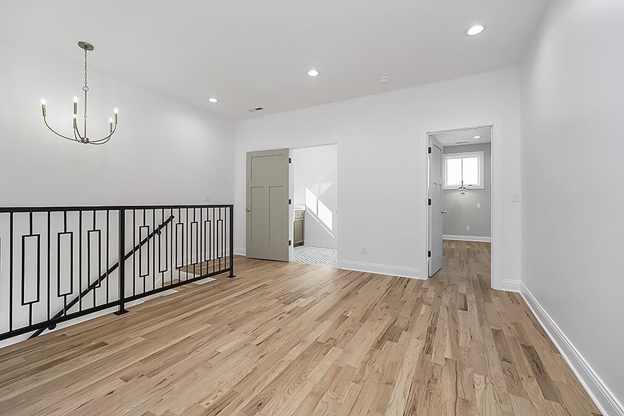 Upstairs Loft with Light Wood Flooring, Modern Chandelier, and Black Stair Railing in a Custom Home by Gem Homes Indianapolis