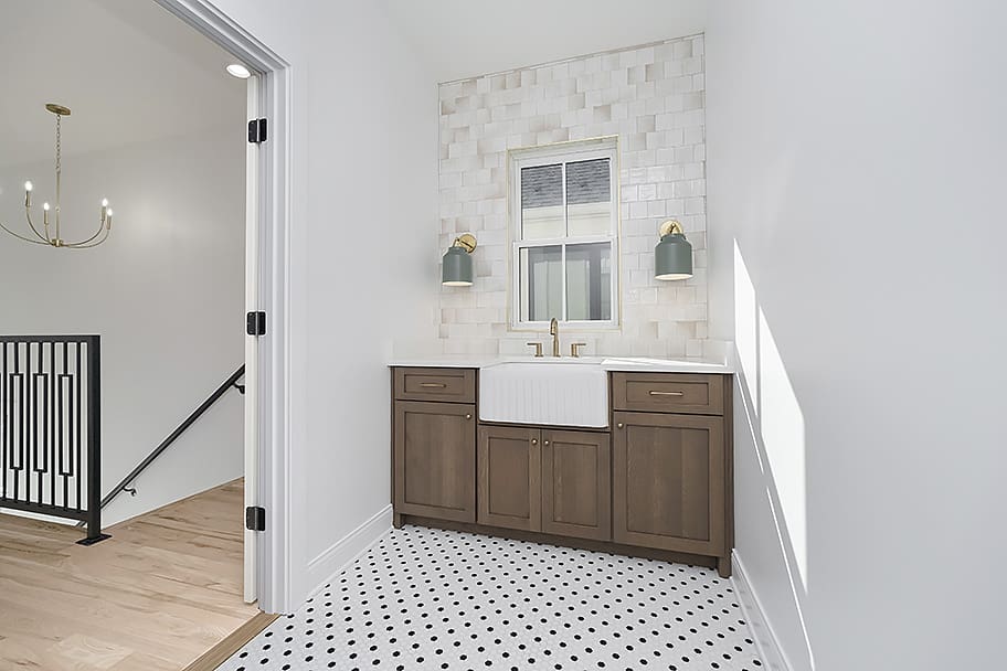 Laundry Room with White and Black Circle Tile, Laundry Sink, and Beige Square Glossy Tile Walls in a Custom Home by Gem Homes Indianapolis