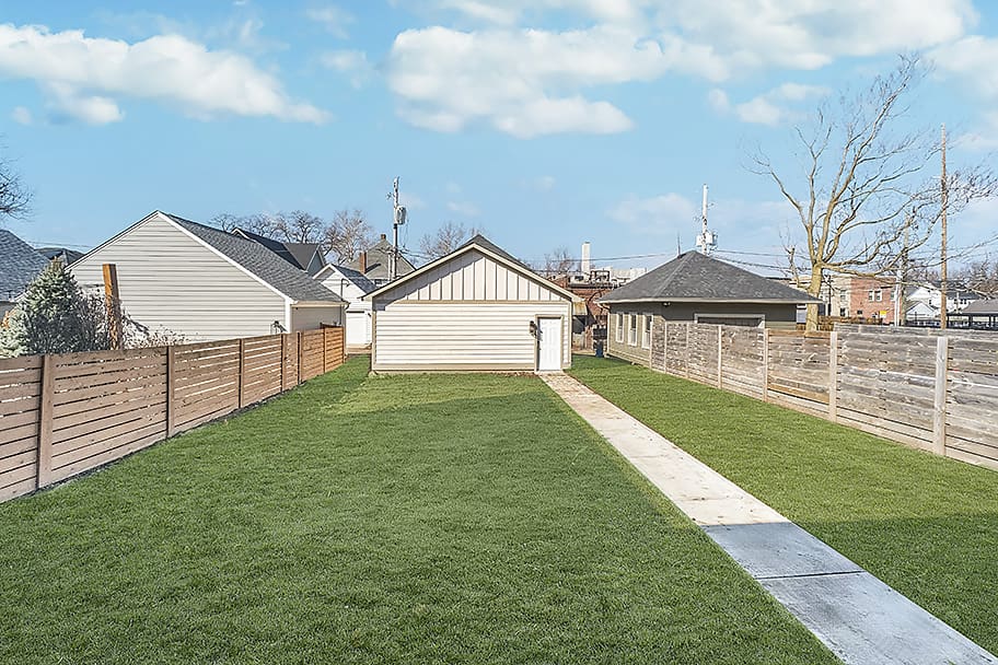 Artificial Grass Lawn with White Detached Garage and Fence in Backyard of Custom Home by Gem Homes Indianapolis